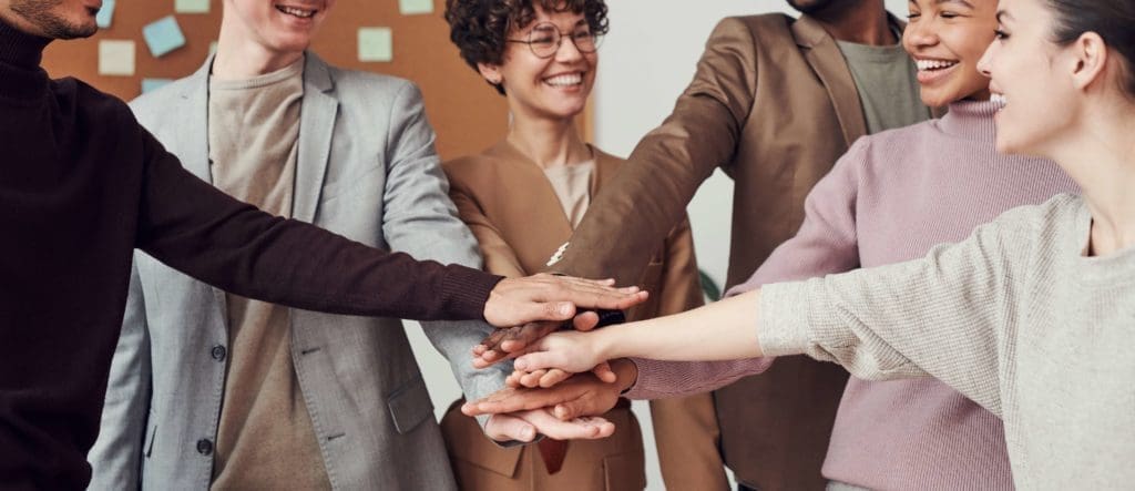4 Key Steps To Ensure Your HOA Board Meeting Doesn't Fall Apart 1 HOA Board Meeting - picture of a group of people smiling and putting their hands together