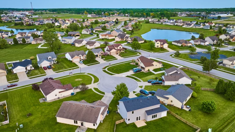 Benefits of HOAs: picture of an HOA with houses, green area, swimming pool, lake and cars.
