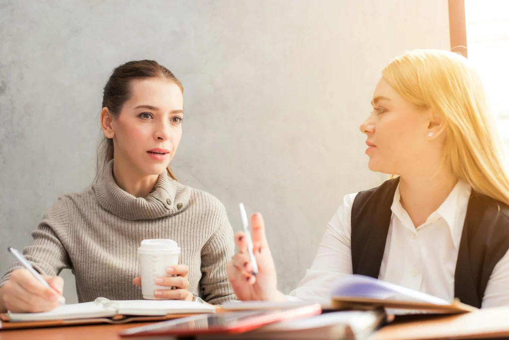 10 Questions to Ask the HOA Before Moving In 1 Two women sitting down reviewing questions to ask the HOA
