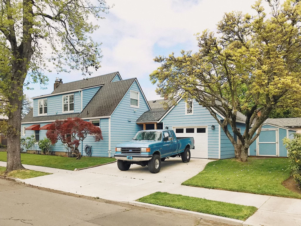 HOA Parking Problems: 5 Easy Tips for Driving Change 1 HOA Parking problem represented by a blue truck parked in front of a garage