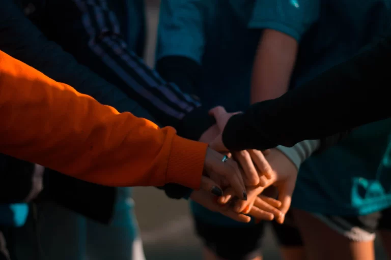 5 people with their hands on top of each other in a circle - your HOA transition team