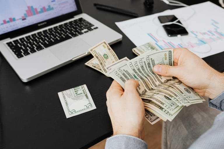 California AB 130 – a man counting cash while using a laptop